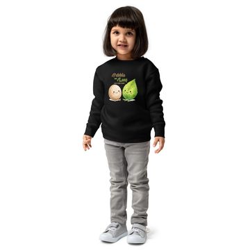 Smiling child wearing a black sweater with cute pebble and leaf design.