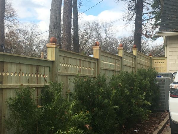 A wooden fence with basketball finials along a residential street.