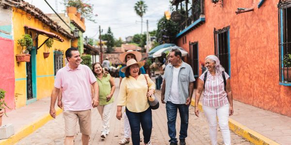 A group of six cheerful older adults walking down a colorful street together.
