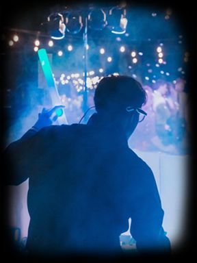 Silhouette of a person holding a glowing light stick at a vibrant event.