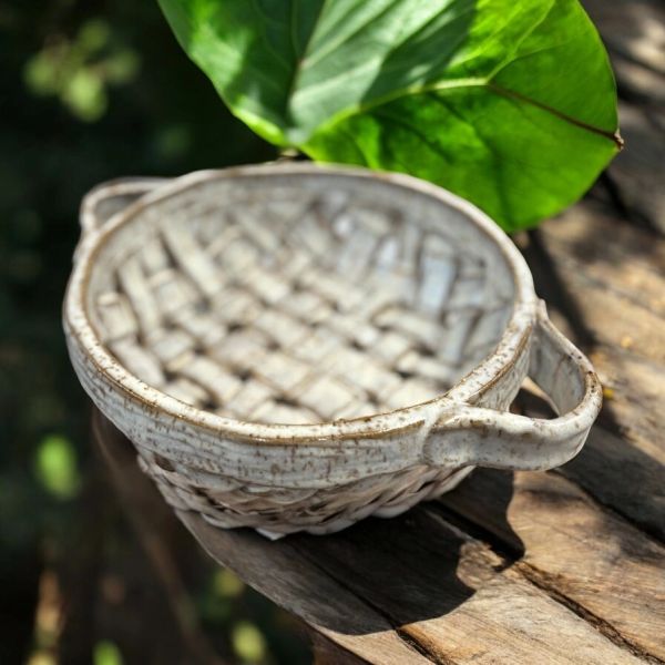 A ceramic basket-shaped dish with handles on a wooden surface.