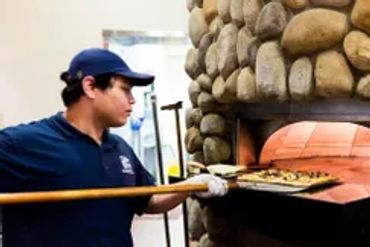 a man putting a pizza in the oven 