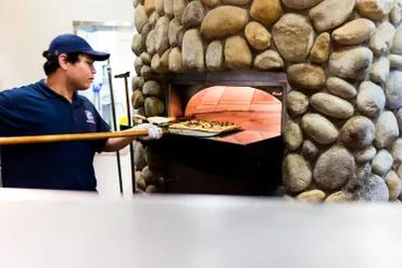 a man putting a pizza in the oven 