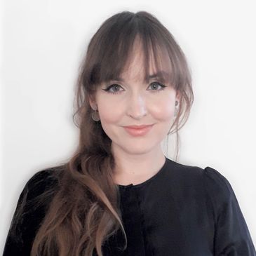 Portrait of a woman with long brown hair and bangs, smiling gently.