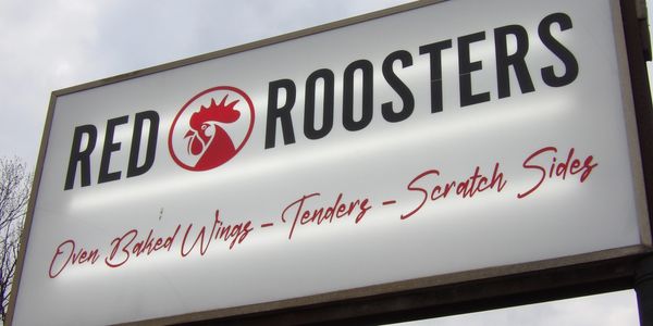 Signboard of Red Roosters advertising baked wings and tenders.