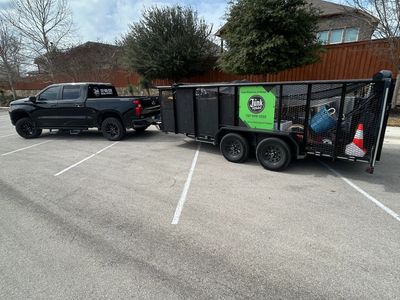 Black pickup truck with a trailer parked across multiple parking spaces.