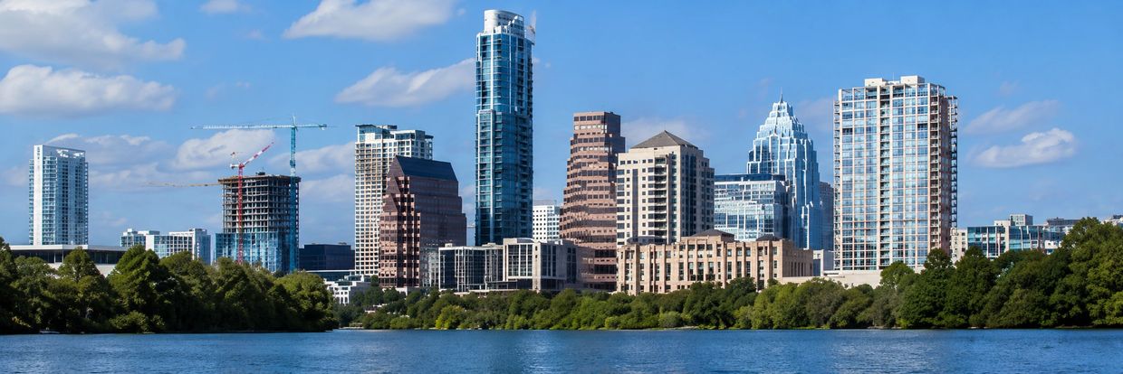 Austin skyline with modern buildings by a river under a blue sky.