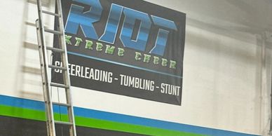 Two ladders against a wall with a cheerleading banner above.