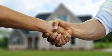 Handshake in front of a house.