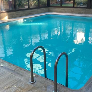 Piscina interior con peldaños metálicos y agua clara.