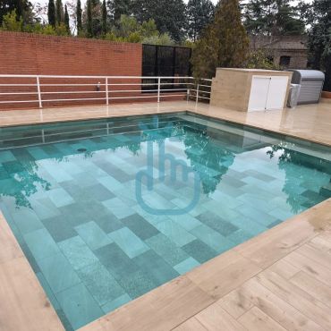 Piscina limpia con borde de madera y muro de ladrillos.