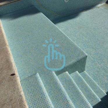 Escalera y plataforma dentro de una piscina cubierta de mosaicos.