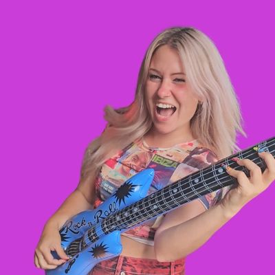 Caitlin Evans enthusiastically pretending to play a blue blow-up guitar prop.