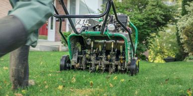 A person mowing a lawn with a green mower.