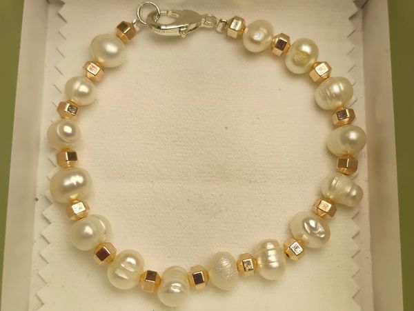 Elegant pearl and gold bead bracelet in a jewelry box.
