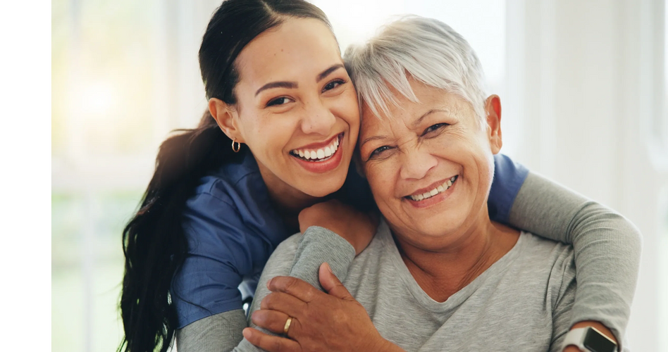 A professional caregiver hugging and smiling with an elderly woman, both are joyful, like each other and are happy to spend time together.