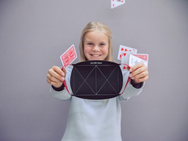 Girl holding The Card Buddy while a card game is being dropped on her.