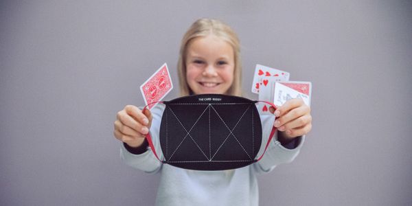 Girl holding up The Card Buddy while card games are dropping on her.