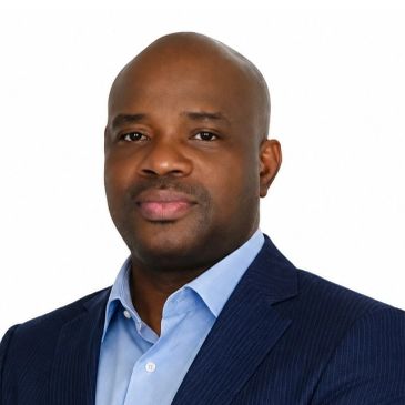 Professional portrait of a confident man in a suit against a white background.