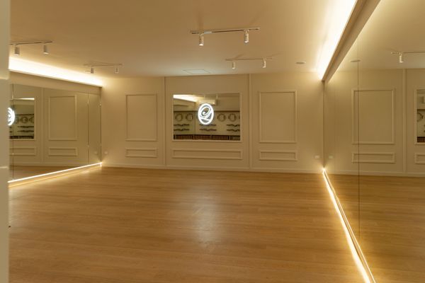 Sala de entrenamiento con espejos y suelo de madera.