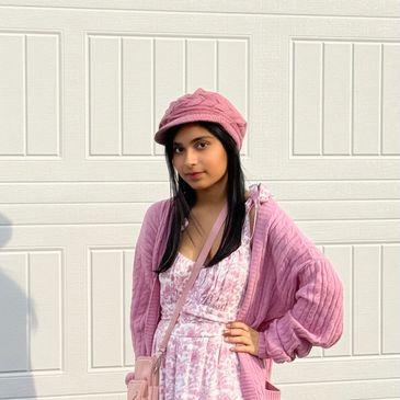 Young woman wearing a pink outfit and hat standing outdoors.