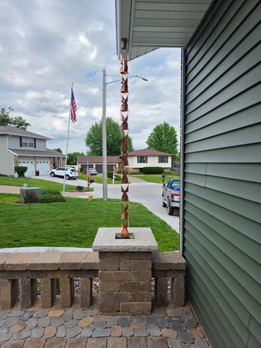 Decorative copper rain chain hanging from the roof.