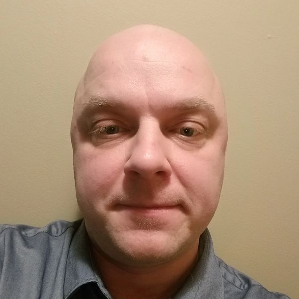 Bald man wearing a collared shirt.