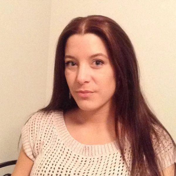 Woman with long brown hair wearing a knitted beige top.