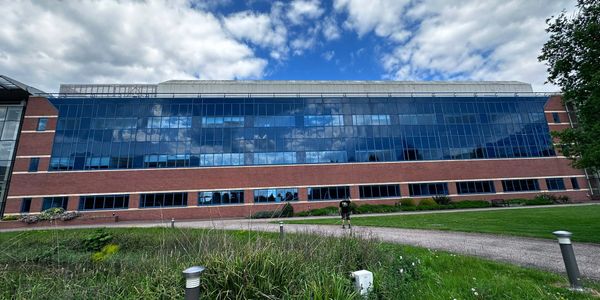 Modern building with reflective glass windows under a partly cloudy sky.