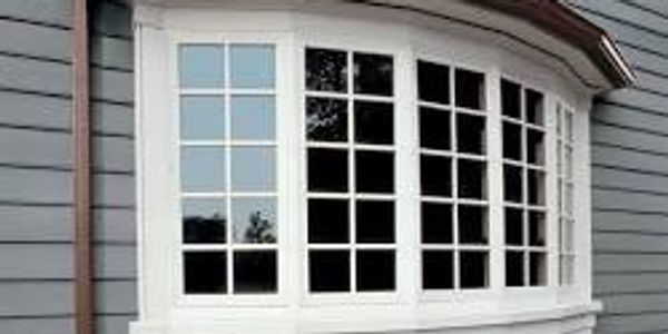 White framed bay window on gray house exterior.