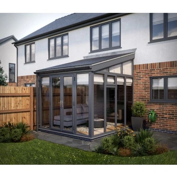 Modern conservatory with glass walls extending from a brick house, overlooking a garden.