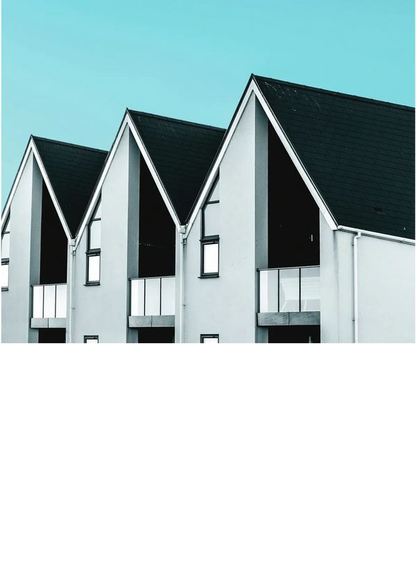 Modern row of houses with triangular roofs against a clear blue sky.