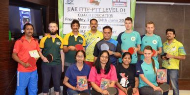 Group photo of table tennis coaches holding paddles and certificates.