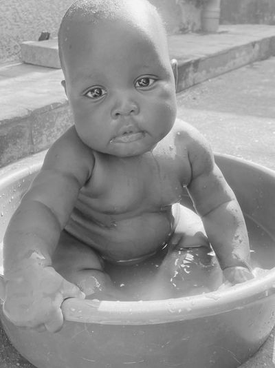Baby sitting in large bowl of water. 