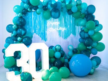 Blue and green balloon arch with a large '30' and 'Happy Birthday' sign.