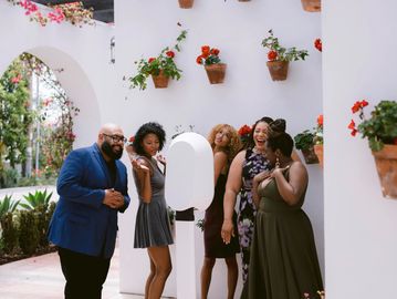 Group of friends enjoying a moment with a photo booth at a garden party.