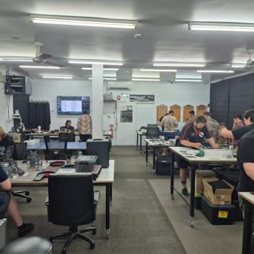 People working in a well-lit office with computers and equipment.