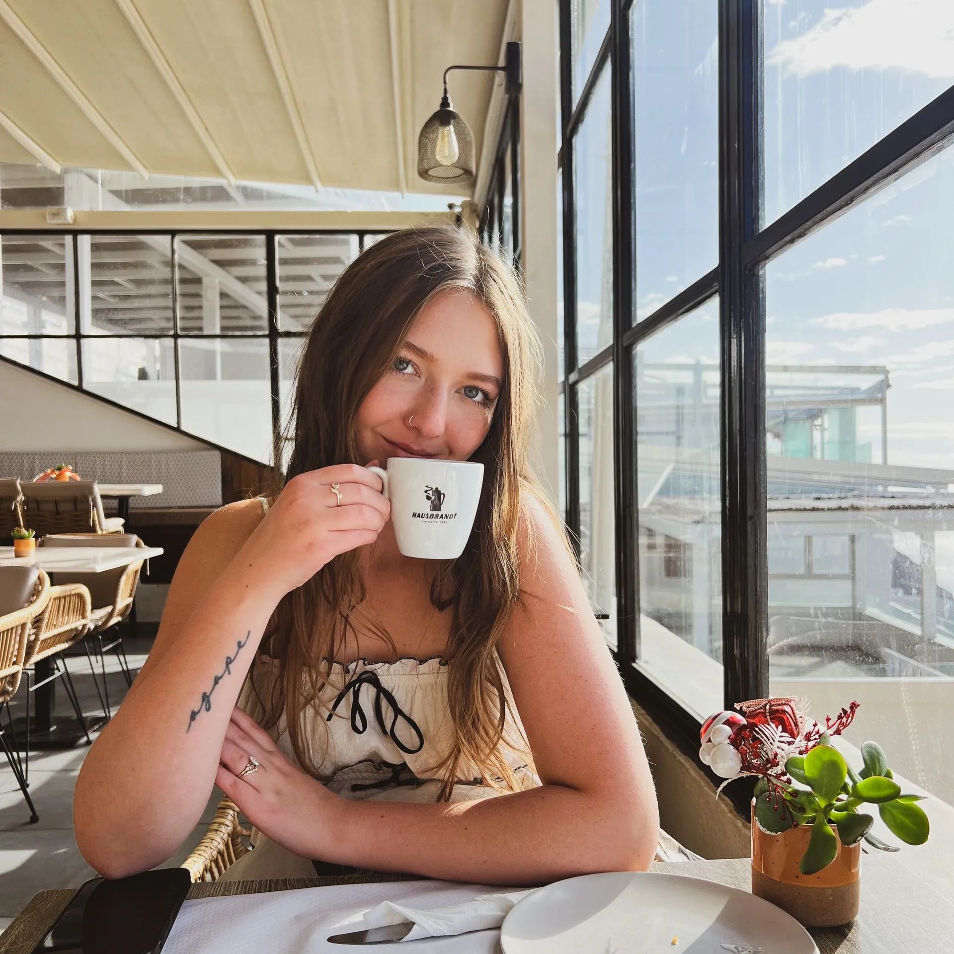Young woman enjoying coffee in a bright café by the window.