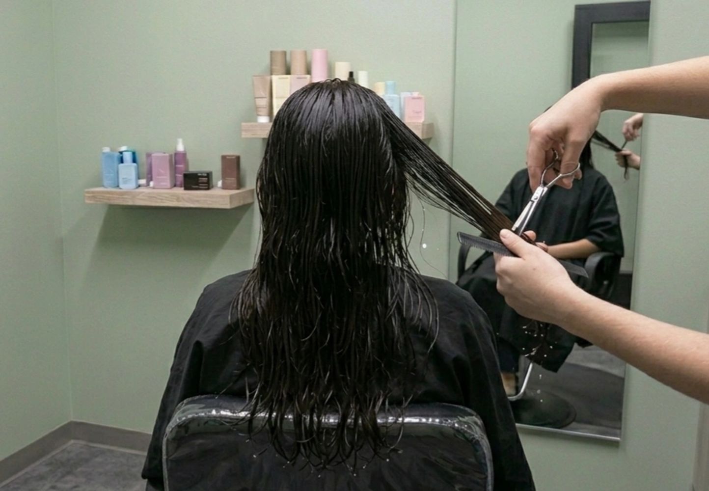 Person getting a wet haircut in a salon with hairdresser trimming hair.