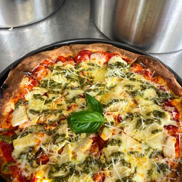 A baked pizza with cheese and green pesto.