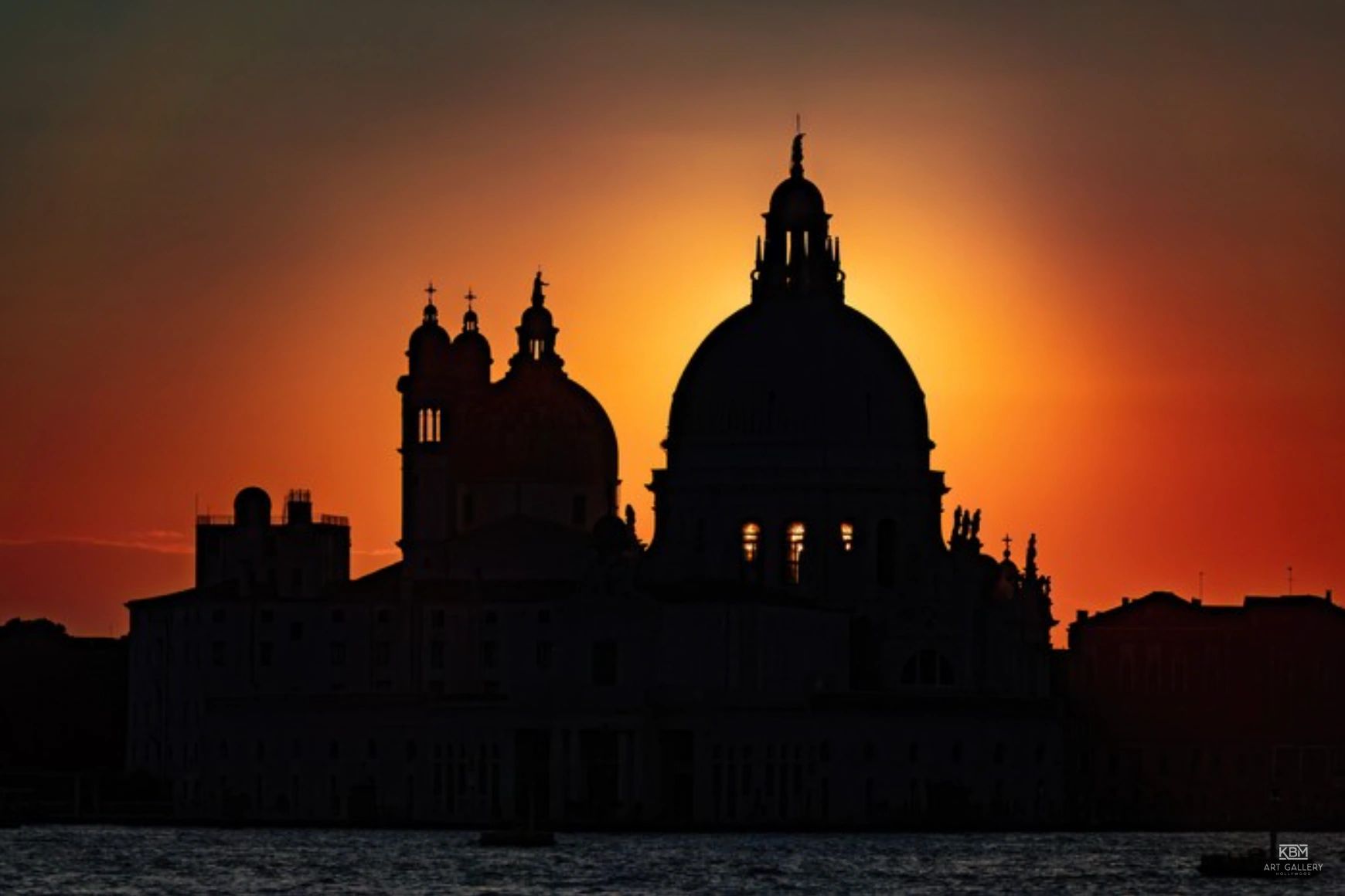Silhouette of a domed building at sunset over water.