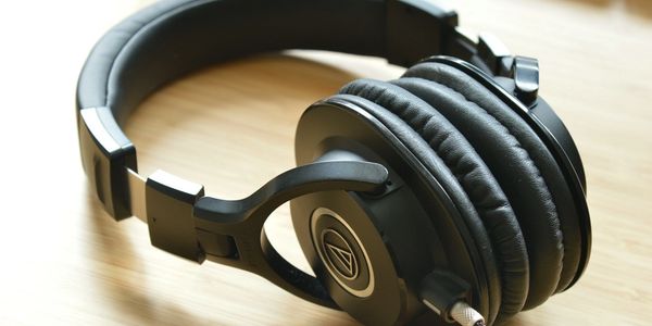Black over-ear headphones resting on a wooden surface.