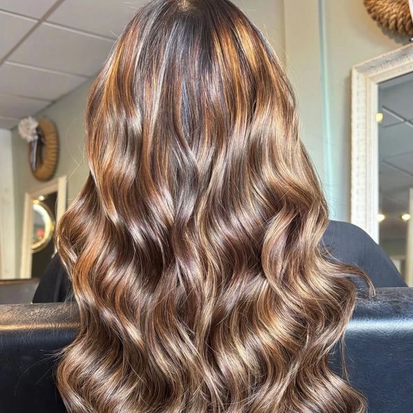 Shiny, wavy brunette hair with caramel highlights.