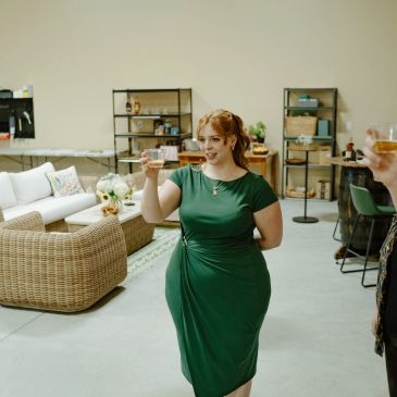 Woman in green dress toasting with a glass.