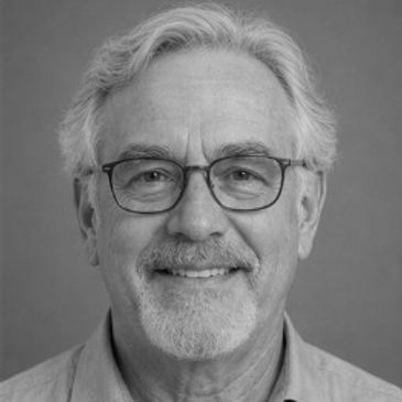 Smiling elderly man with glasses and gray hair.