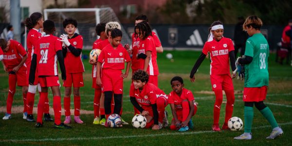 Youth soccer team in red uniforms preparing on the field.