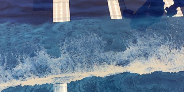 Abstract blue and white textured surface with reflections of ceiling lights and a person. Epoxy flooring solutions, durable floor coatings, garage floor transformation
