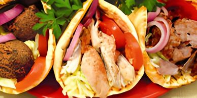 Three pita sandwiches, one with falafel, and two with chicken and vegetables.