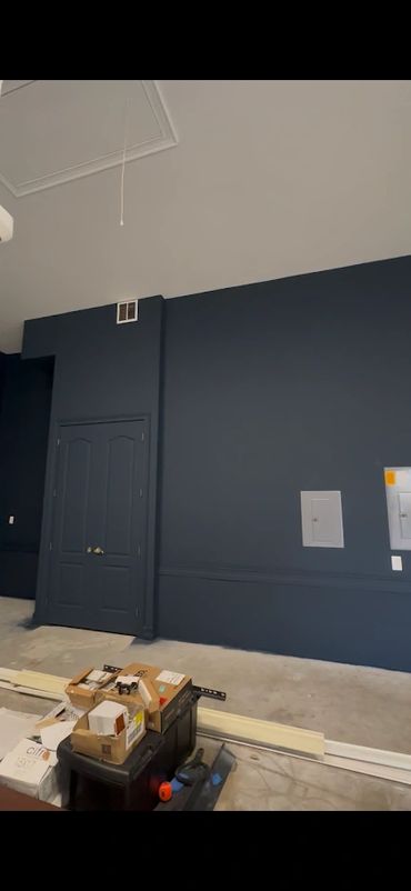 Dark blue wall with a closed door and some construction materials on the floor.