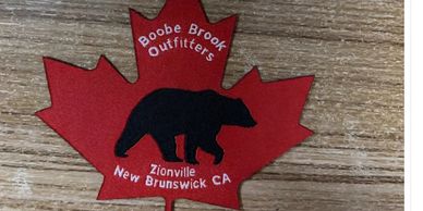 Maple leaf patch with bear silhouette and outfitters text.